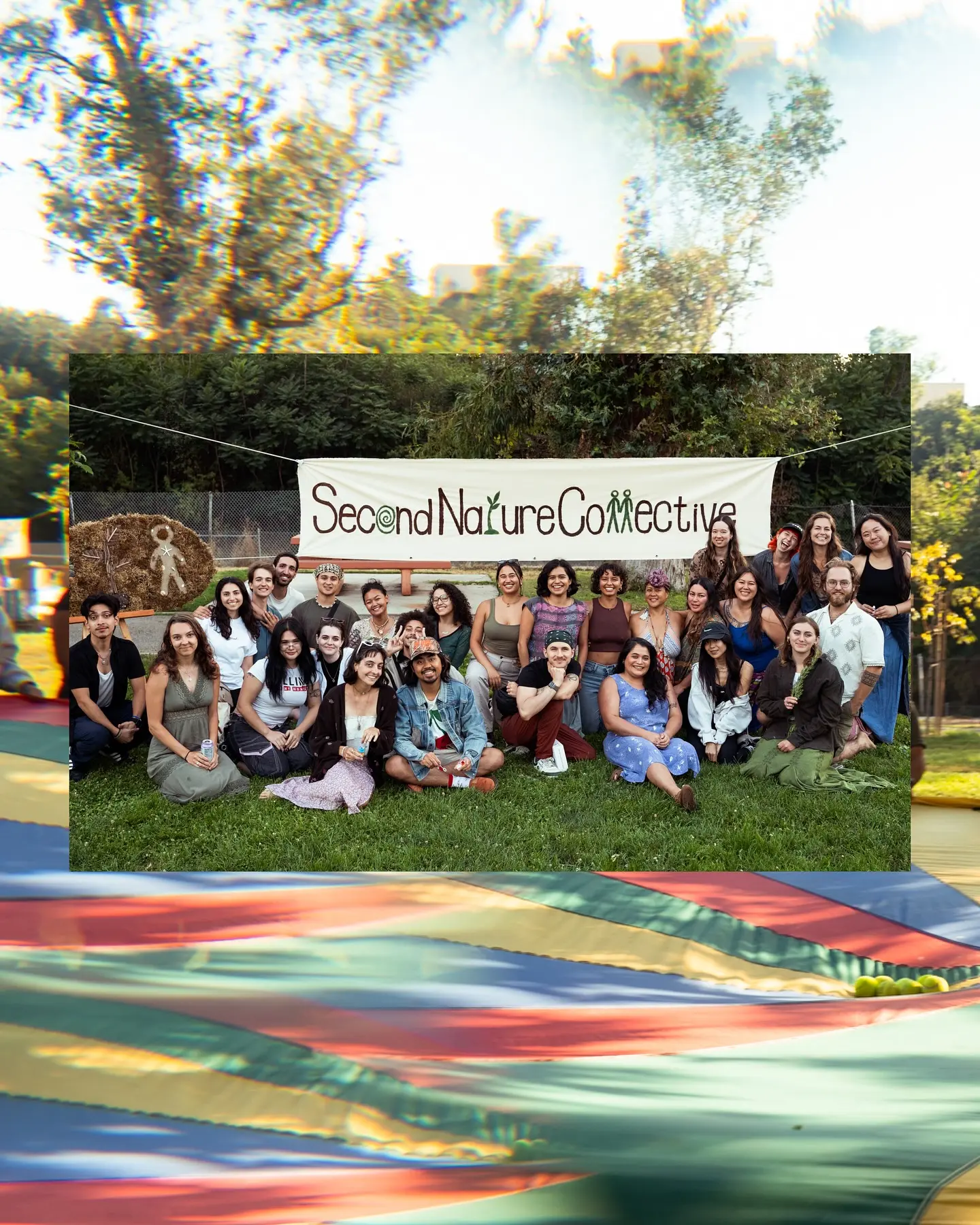 A large group portrait in front of the hand-painted Second Nature Collective banner