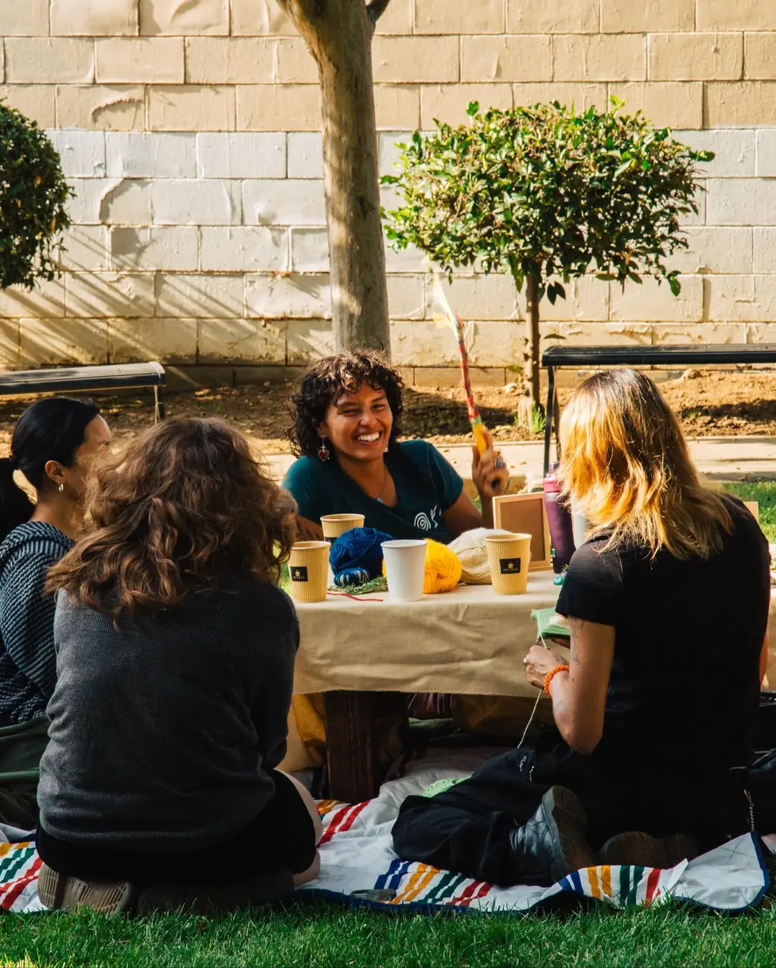 Friends seated together at a community table outdoors