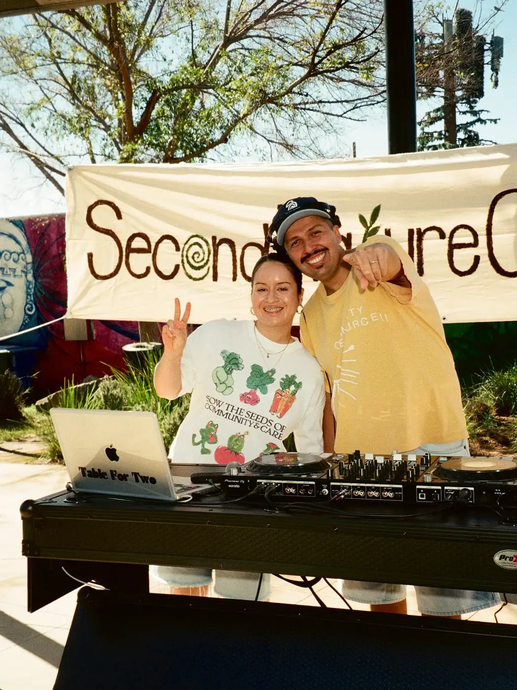 A DJ playing in front of a Second Nature Collective banner
